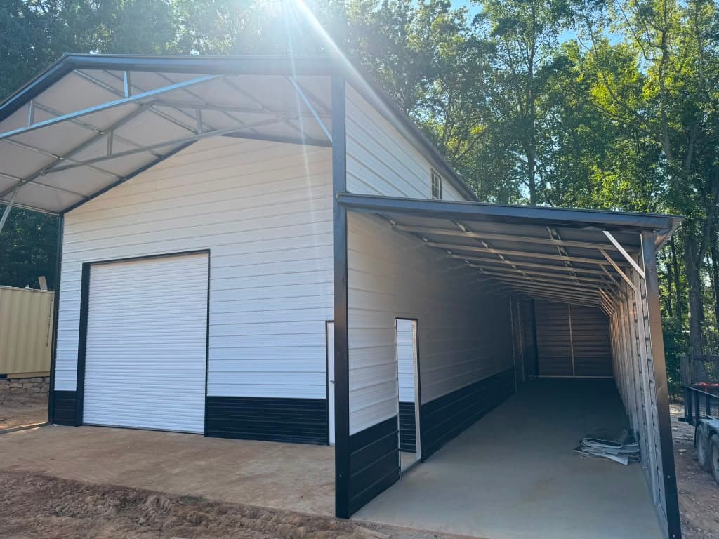 White metal garage with black wainscot and an open lean-to