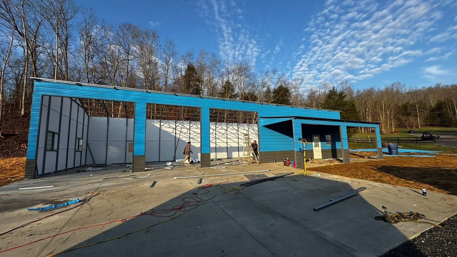 A Frontier steel building going up on a prepared, level concrete pad — crew installing wall panels on install day.